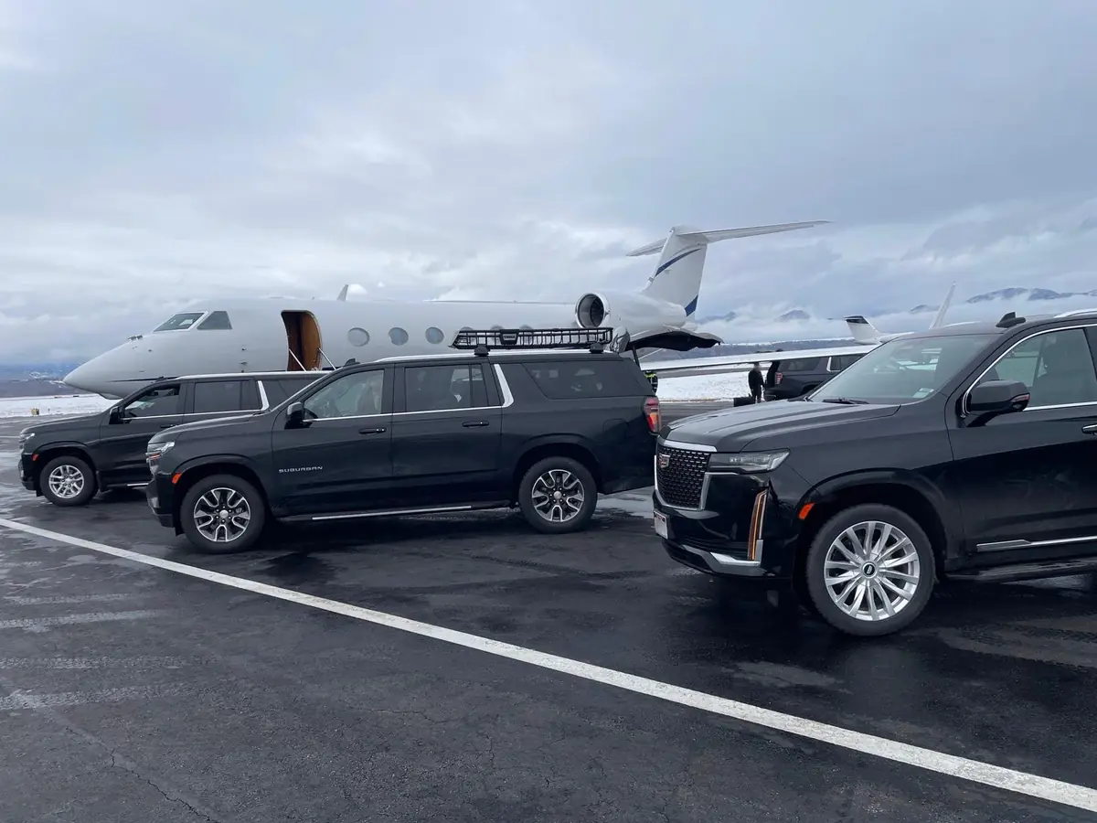 Black full-size SUV waiting on the tarmac beside a parked private jet