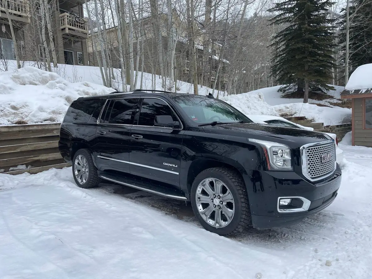 Black full-size SUV parked on packed snow outside a mountain condo building in Colorado